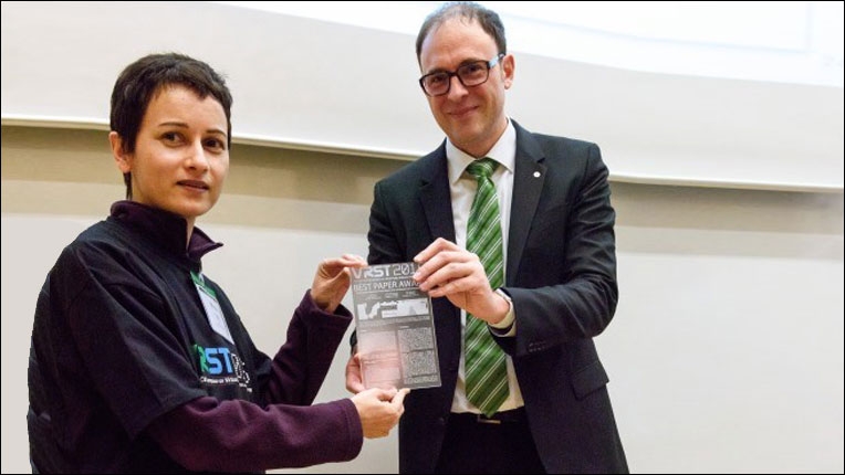 Hans-Joachim Hof hands the Best Paper Award to Misha Sra, a graduate student from MIT Media Lab and first author of the paper.